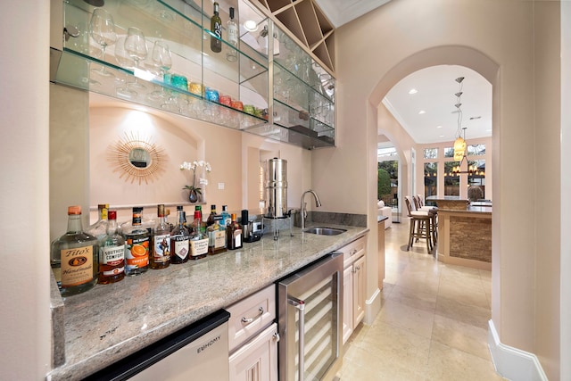 bar with arched walkways, a sink, wine cooler, bar area, and crown molding