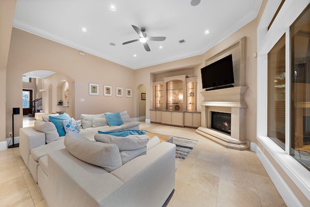 living room with visible vents, arched walkways, a glass covered fireplace, and crown molding