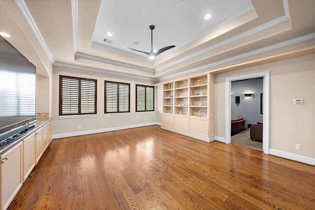 interior space with a tray ceiling, wood finished floors, and ceiling fan