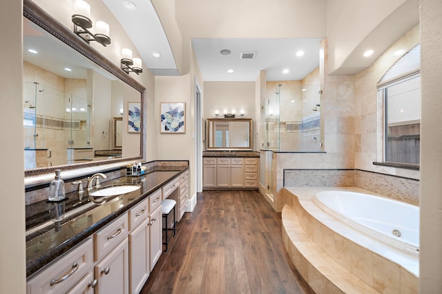 bathroom featuring visible vents, a stall shower, a tub with jets, and wood finished floors