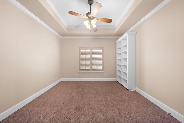 carpeted spare room featuring ceiling fan, baseboards, a tray ceiling, and ornamental molding