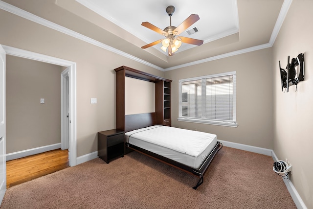 bedroom with light carpet, visible vents, a raised ceiling, and baseboards