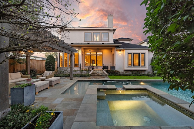 back of property at dusk with an outdoor pool, stucco siding, a chimney, and fence