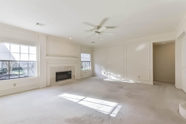 unfurnished living room with a glass covered fireplace, a decorative wall, visible vents, and carpet floors