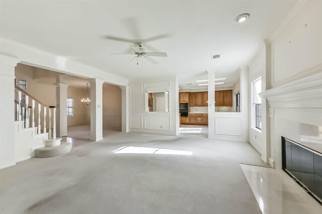 unfurnished living room featuring a high end fireplace, a decorative wall, light colored carpet, and ornate columns