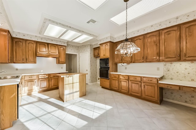 kitchen with visible vents, wallpapered walls, a center island, brown cabinetry, and black appliances