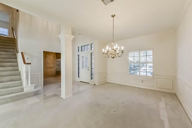 unfurnished dining area featuring visible vents, ornate columns, stairs, carpet flooring, and a chandelier