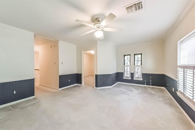 carpeted spare room featuring visible vents, wallpapered walls, ceiling fan, and a wainscoted wall