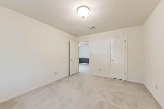 unfurnished room with light colored carpet, visible vents, and baseboards