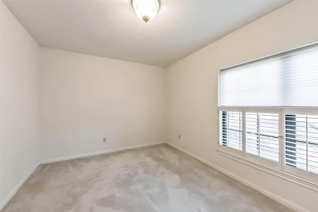 spare room featuring baseboards and light carpet