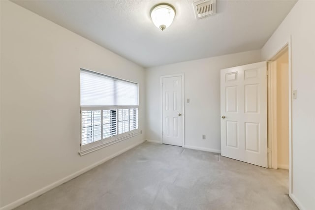 unfurnished bedroom featuring visible vents, light colored carpet, and baseboards