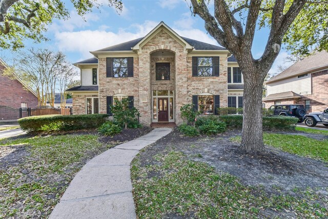 traditional-style home featuring brick siding and fence