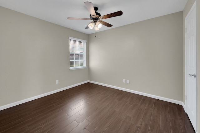 spare room featuring baseboards, dark wood-style floors, and a ceiling fan