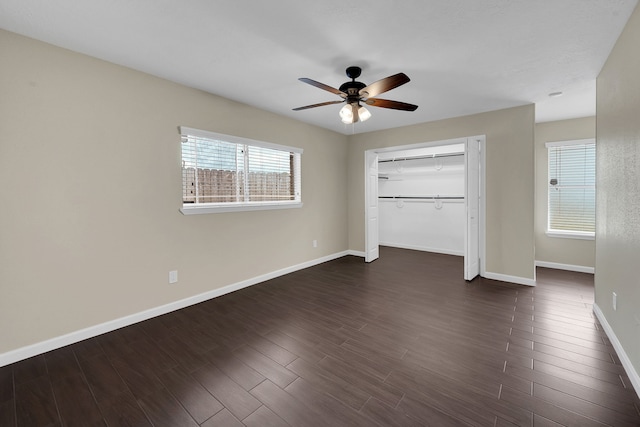 unfurnished bedroom with a closet, baseboards, a ceiling fan, and dark wood-style flooring