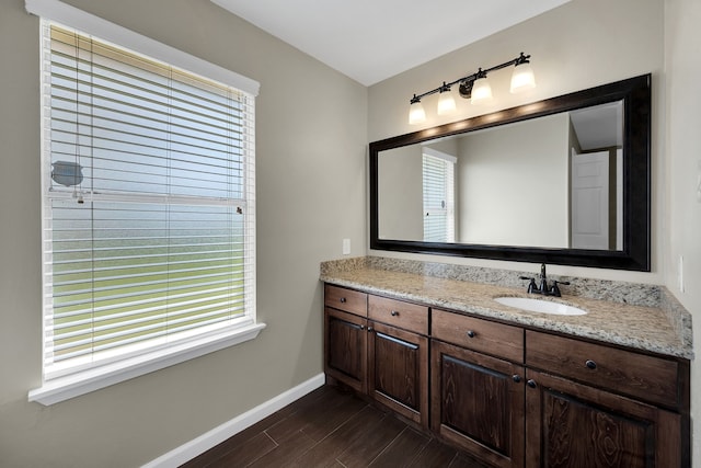 bathroom featuring a wealth of natural light, vanity, baseboards, and wood finished floors