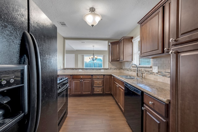 kitchen featuring visible vents, backsplash, wood finished floors, black appliances, and a sink