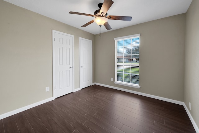 unfurnished bedroom featuring ceiling fan, baseboards, and dark wood-style floors