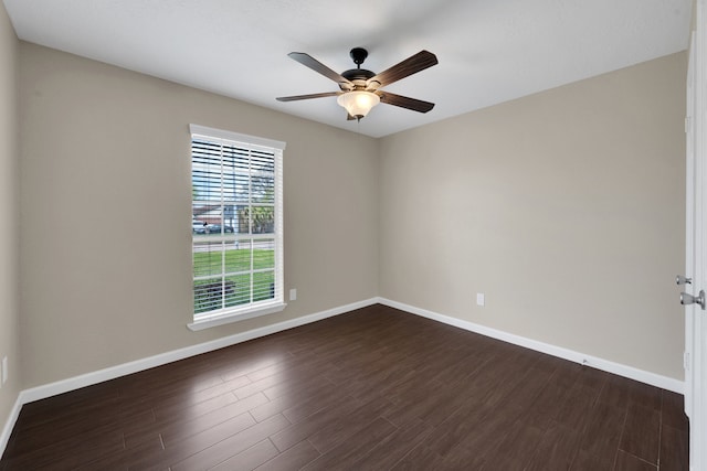 unfurnished room with dark wood finished floors, a ceiling fan, and baseboards