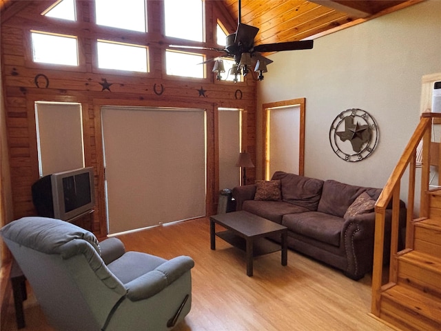 living area featuring high vaulted ceiling, a ceiling fan, wooden ceiling, light wood finished floors, and stairs