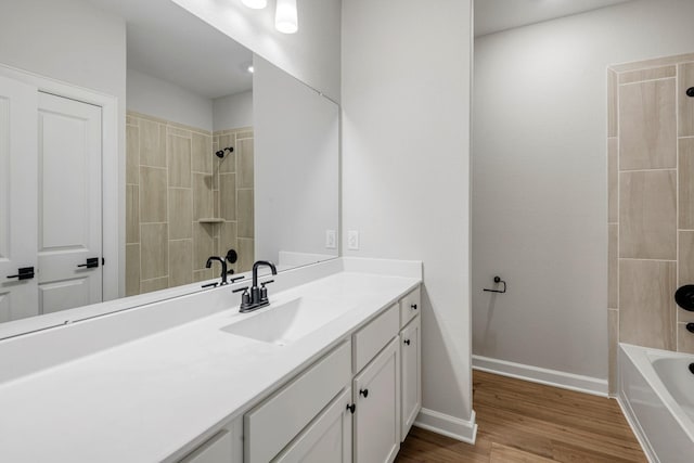 full bath with baseboards, shower / washtub combination, wood finished floors, and vanity