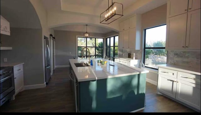 kitchen featuring an island with sink, a sink, backsplash, appliances with stainless steel finishes, and light countertops