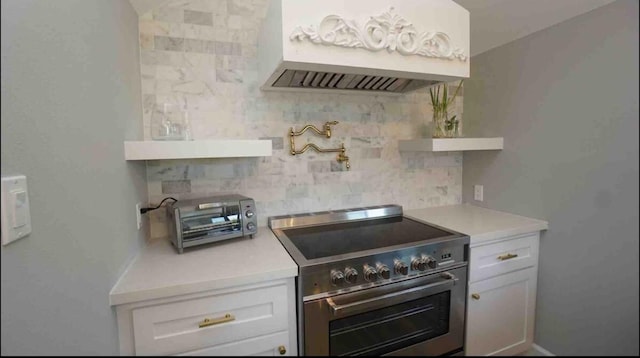 kitchen with custom exhaust hood, light countertops, white cabinets, high end stainless steel range oven, and tasteful backsplash