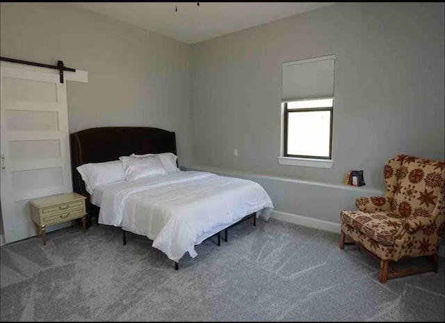 carpeted bedroom with a barn door and baseboards