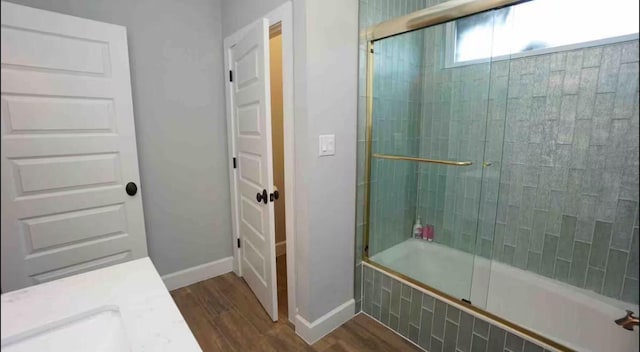 bathroom with tiled shower / bath, baseboards, and wood finished floors