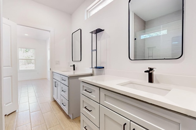 full bath with a shower stall, two vanities, and a sink