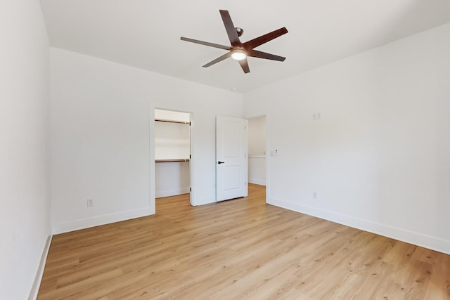 unfurnished bedroom featuring a ceiling fan, a closet, light wood finished floors, baseboards, and a spacious closet