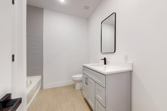 bathroom with visible vents, baseboards, toilet, wood finished floors, and vanity