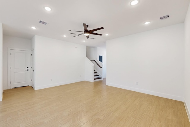 unfurnished room featuring visible vents, stairway, light wood-type flooring, and ceiling fan