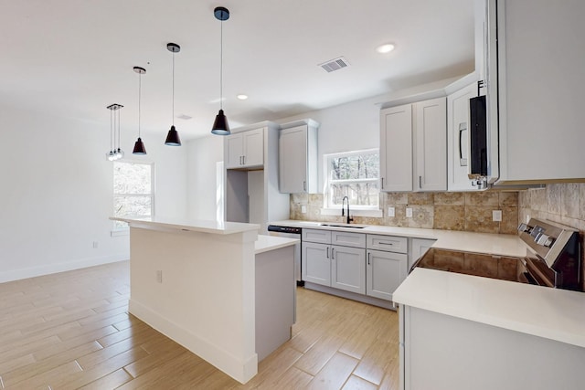 kitchen featuring tasteful backsplash, visible vents, a center island, electric stove, and a sink