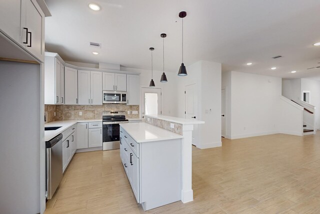 kitchen featuring light wood finished floors, a kitchen island, recessed lighting, decorative backsplash, and appliances with stainless steel finishes