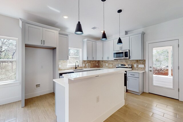 kitchen featuring tasteful backsplash, visible vents, light wood finished floors, appliances with stainless steel finishes, and a sink