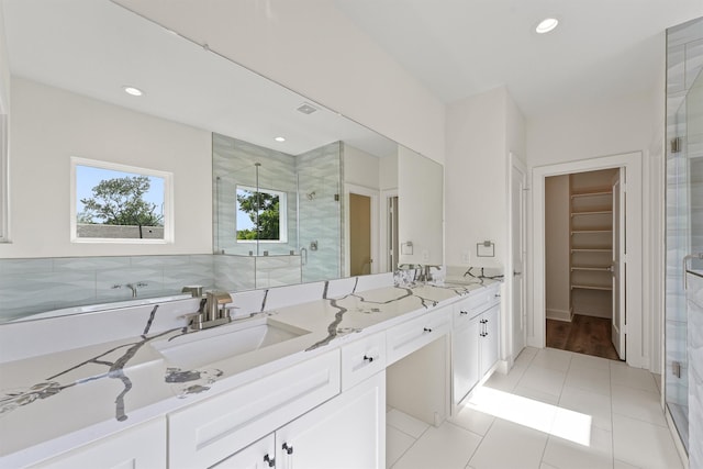 bathroom with a spacious closet, a shower stall, double vanity, recessed lighting, and a sink