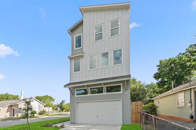 contemporary house featuring a garage, fence, board and batten siding, and driveway