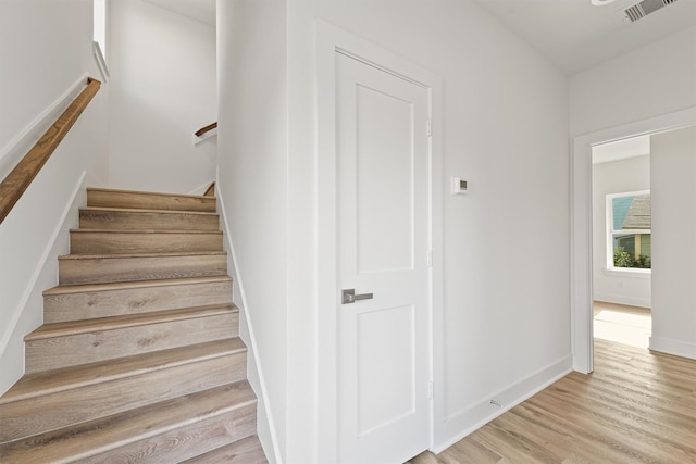 staircase featuring wood finished floors, visible vents, and baseboards