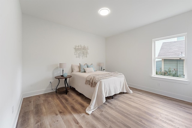 bedroom with light wood-type flooring and baseboards