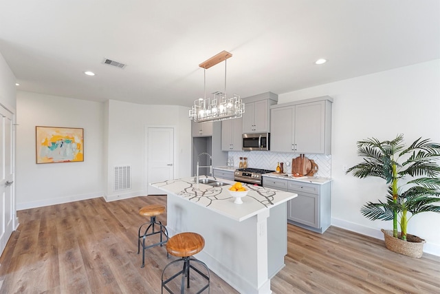 kitchen featuring stainless steel appliances, tasteful backsplash, gray cabinetry, and light countertops