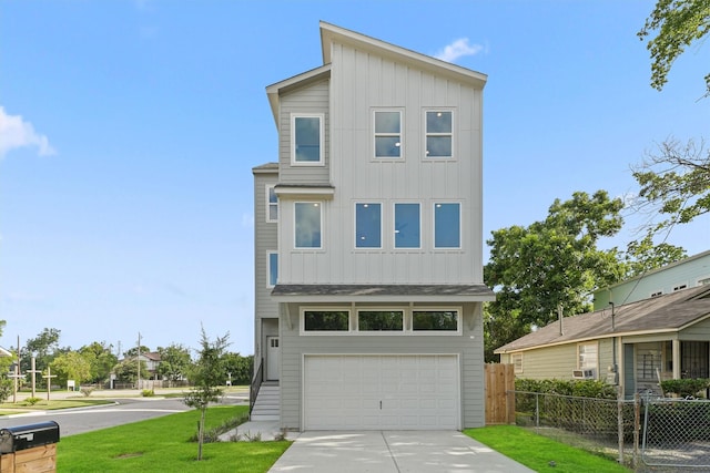 contemporary house featuring fence, an attached garage, concrete driveway, a front lawn, and board and batten siding