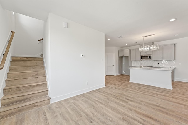 interior space featuring light wood finished floors, stairway, recessed lighting, and baseboards