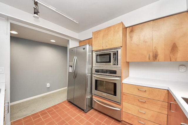 kitchen featuring light countertops, a warming drawer, baseboards, and appliances with stainless steel finishes