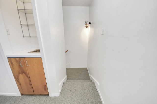 stairway featuring baseboards and carpet floors