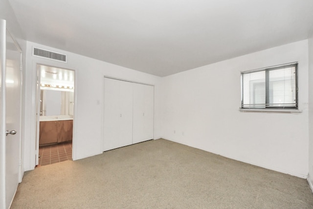 unfurnished bedroom featuring visible vents, carpet floors, a closet, and ensuite bathroom