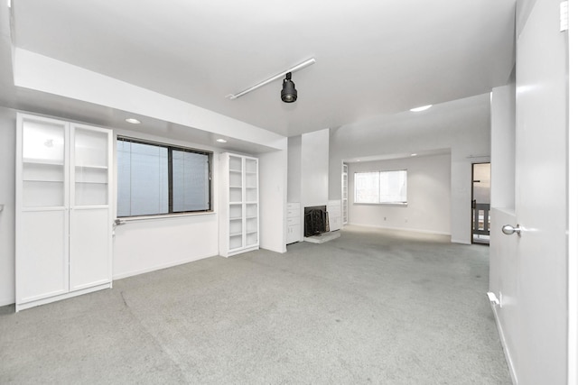 unfurnished living room with recessed lighting, rail lighting, baseboards, and carpet