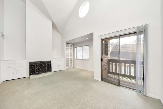 unfurnished living room featuring a fireplace with raised hearth, high vaulted ceiling, baseboards, and carpet floors