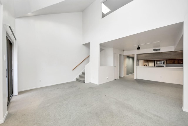 unfurnished living room with visible vents, baseboards, stairs, carpet floors, and a towering ceiling