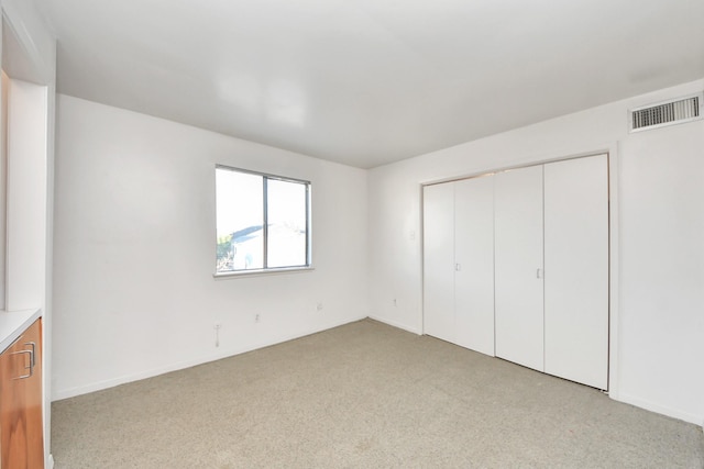 unfurnished bedroom featuring light carpet, visible vents, and a closet