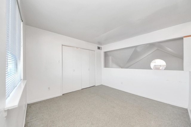 unfurnished bedroom with vaulted ceiling, multiple windows, visible vents, and carpet floors